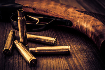 Rifle with empty shells lie on a wooden table