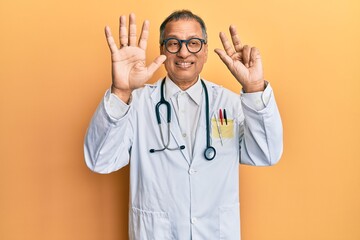 Middle age indian man wearing doctor coat and stethoscope showing and pointing up with fingers number eight while smiling confident and happy.