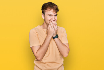 Young caucasian man wearing casual clothes laughing and embarrassed giggle covering mouth with...