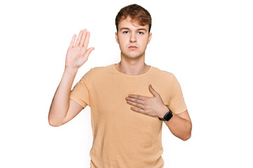 Young caucasian man wearing casual clothes swearing with hand on chest and open palm, making a...
