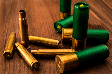 Empty shells from the rifle and 12 gauge bullets lying on a wooden table