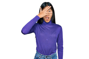 Beautiful young asian woman wearing casual clothes peeking in shock covering face and eyes with hand, looking through fingers with embarrassed expression.