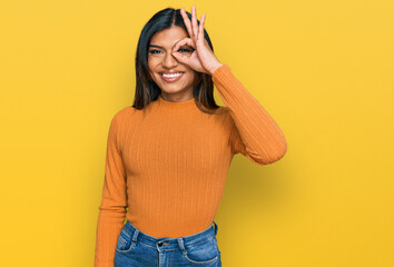 Young latin transsexual transgender woman wearing casual clothes doing ok gesture with hand smiling, eye looking through fingers with happy face.