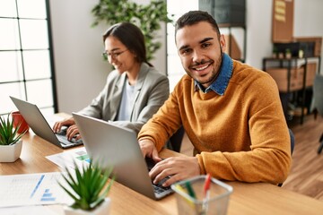 Two business workers smiling happy working sitting on desk at the office.