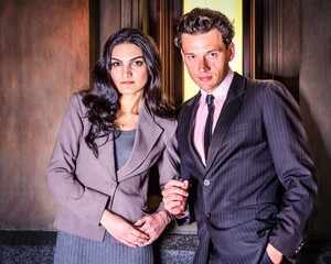 Young Businessman and Businesswoman. A couple of young businessman and businesswoman are standing outside by a window, talking and taking a work break.