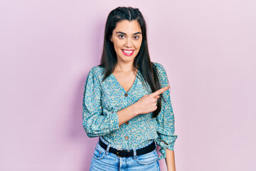 Young hispanic girl wearing casual clothes smiling cheerful pointing with hand and finger up to the side