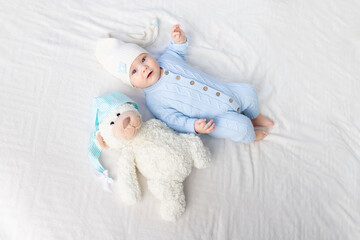 happy baby on the bed in a hood. Textiles and bedding for children. Newborn baby with a toy bear