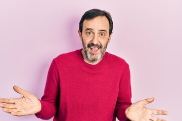 Middle age hispanic man wearing casual clothes clueless and confused expression with arms and hands...