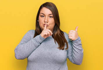 Beautiful brunette plus size woman wearing casual clothes asking to be quiet with finger on lips pointing with hand to the side. silence and secret concept.