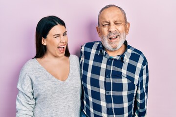 Hispanic father and daughter wearing casual clothes winking looking at the camera with sexy expression, cheerful and happy face.