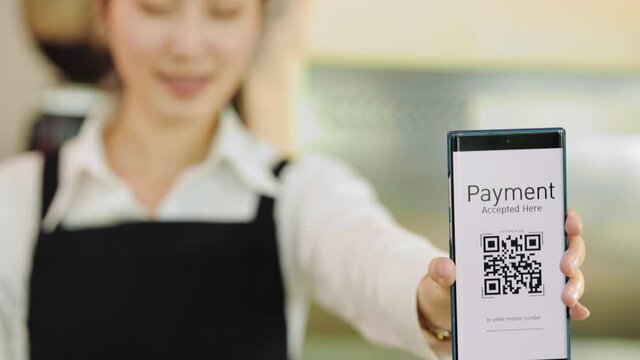 Customer paying with qr code on smartphone screen NFC payment technology at coffee shop.Midsection of female staff showing contactless menu QR code on digital mobile.