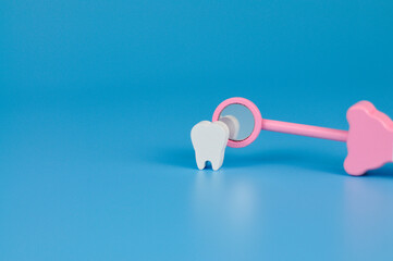 model of a tooth on a blue background for pediatric dentistry. examination of the teeth with a mirror. dental care