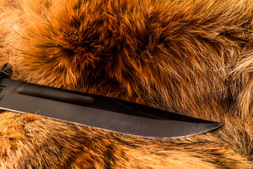 Battle hunting knife lying on the fur of the animal. View close-up