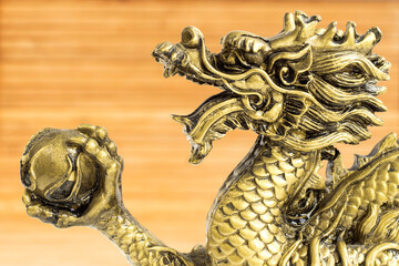 Bronze dragon. Gold statuette on a wooden background.