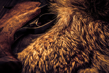 Hunting rifle lying next to the animal's fur produced. View close-up