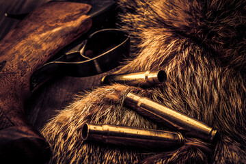 Hunting rifle lying next to the animal's fur produced with the casings from bullets. View close-up,...