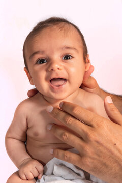 Two month old Caucasian baby sitting smiling looking at camera. Studio photos with white background