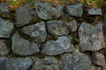 a wall of rough granite stones, with moss in the cracks