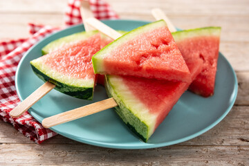 Watermelon slices popsicles on blue plate on rustic wooden table