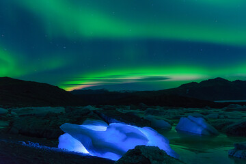 Northern light and lake with a blue icebergs. Aurora borealis above a glacier. Iceland. 