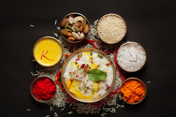 Close-up of Creamy rice Kheer(khir) Garnished with saffron and dry fruits for pooja (spiritually celebration). Indian delicious dessert. Served in a ceramic black bowl. Top View on black background.