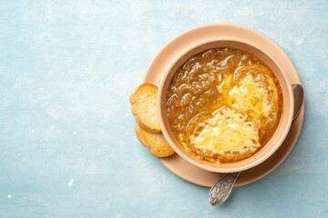Traditional french onion soup with baguette and cheese in bowl on concrete background