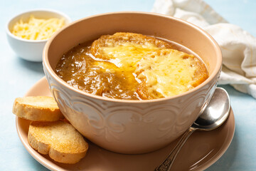 Traditional french onion soup with baguette and cheese in bowl on concrete background