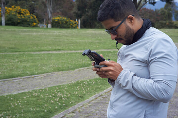 A young man piloting his drone in the park