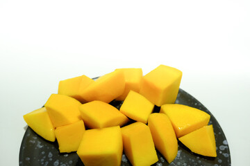 Ripe mangos in a black ceramic dish.