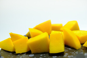 Ripe mangos in a black ceramic dish.