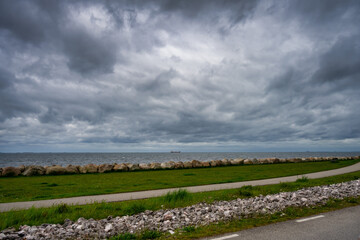 A beautiful, dramatic sky over the ocean. A lawn and stones in a wave breaker in the foreground. Picture from Malmo, Sweden