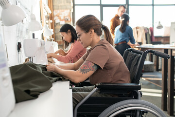 Obraz premium Two females sewing clothes in workshop against colleagues
