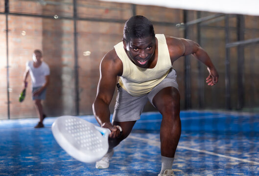 African american man playing paddle tennis on the padel court