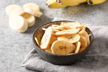Sliced fruits banana chips on light gray background, home drying. Vegan free sugar food. Close up