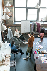 Group of fashion designers discussing sketchc on whiteboard in workshop