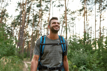 Portrait of smiling young caucasian man trekking in forest