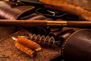 Hunting rifle with leather bandolier and a ramrod with brushes for cleaning weapons lying on a...