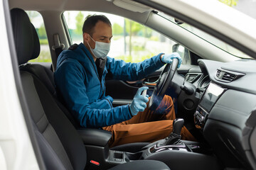 Covid-19 concept. Man drives in car, wears medical gloves, protects himself from bacteria and virus, holds car steering wheel. Coronavirus protection. Transport, quarantine and corona disease.