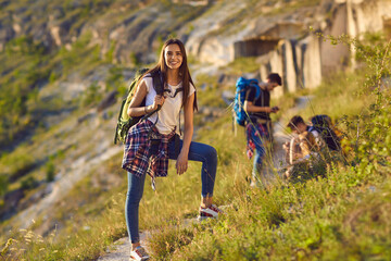 Portrait of a happy and smiling female hiker with a backpack while hiking in the mountains. Girl...