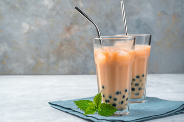 Two glasses of tapioca tea on a gray background with copy space. Homemade milk bubble tea with...