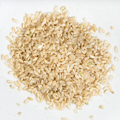 pile of unpolished brown rice close up on gray