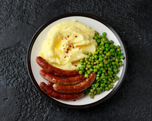 Pork Chipolata sausages with home cooked mashed potato and green peas