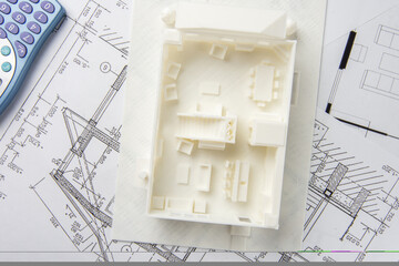 Top view of 3D model of the house interior with furniture, doors, staircase and others details printed on a 3D printer with white filament by FDM technology and calculator.