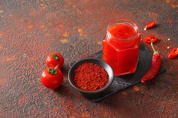 Composition with tasty chili sauce and ingredients on grunge background