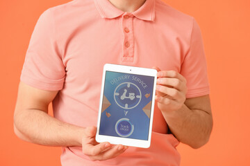 Young man and tablet computer with open page of delivery service application on color background