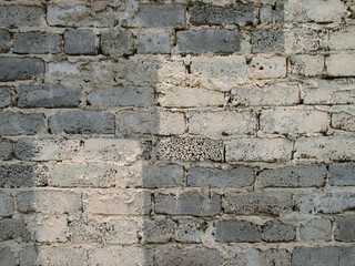 Background from old gray rough brick wall. The top is painted with beige paint. Cement joints. The texture is uneven, rough. 