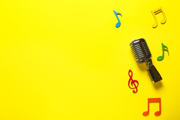 Retro microphone with music notes on color background