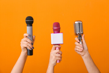 Female hands with modern microphones on color background