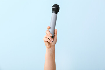 Female hand with modern microphone on color background