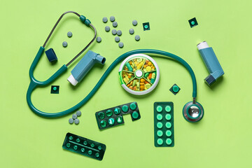 Inhalers with medications and stethoscope on color background